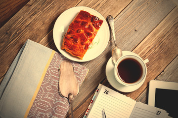 Still life with tea, cake, tablet and plan.