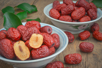 China xinjiang red date with green leaves in wooden bowl cut into half with seeds intact for soup making purposes.