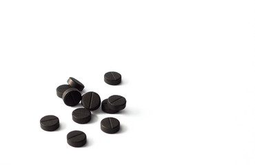 Handful absorbent carbon tablets on white background, left side, copy space on a right side