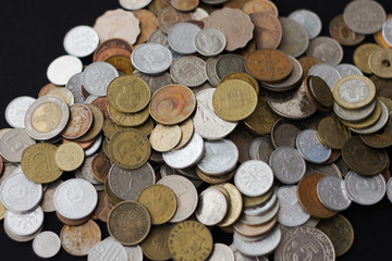 A pile of coins from different countries on a black background