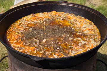 cooking delicious pilaf in a cauldron in the fresh air