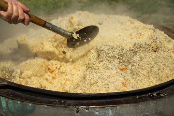 cooking delicious pilaf in a cauldron in the fresh air