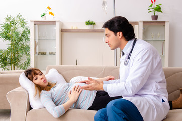 Obraz premium Young handsome doctor visiting pregnant woman at home 