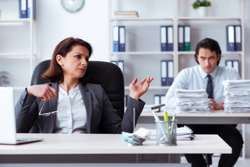 Old female boss and young male employee in the office  