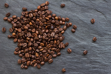 Roasted coffee beans on a natural slate background,  left side, top view