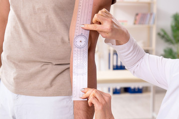 Female doctor checking patient's joint flexibility with goniometer