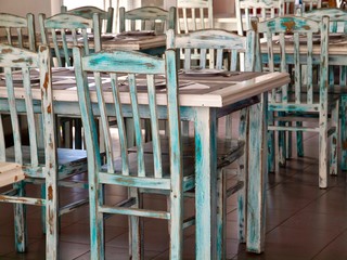 Fototapeta na wymiar Vintage chairs and tables in green out of wood in a restaurant