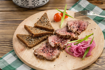 slices of roast beef with rye bread and red onion on wooden table