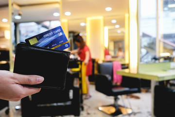 Man payment with credit card at barbers shop, blurred background