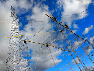 Four workers install a new high-voltage power line. Sunny day, voluminous clouds