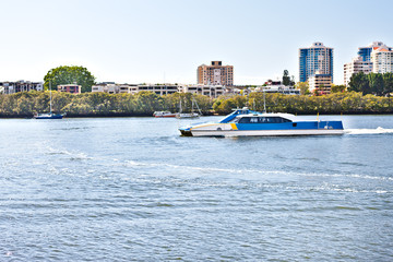 Fototapeta na wymiar Boat runs on the water beside tress and the city