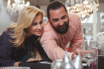 Beautiful elegant mature couple shopping for kitchenware at home goods store, copy space. Attractive woman enjoying buying dishes with her handsome bearded husband. Shopping concept
