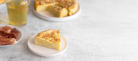  Tortilla,  Spanish omelette made with eggs and potatoes. Traditional Spanish tapa served with slices of jamon, Iberian ham on white background.