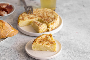  Tortilla,  Spanish omelette made with eggs and potatoes. Traditional Spanish tapa served with slices of jamon, Iberian ham on white background.