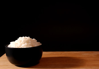 Rice in a bowl on a black background in the studio.