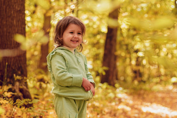 A child in a sports suit is standing, looking away and laughing, 3 years old, childhood