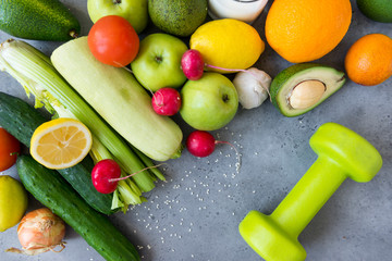 fruits and vegetables , dumbbell on a gray background, apples, zucchini, cucumbers, avocado, radish, garlic, tomato, lemon, orange