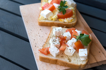2 sandwiches with cheese and tomato and spices on the cutting Board