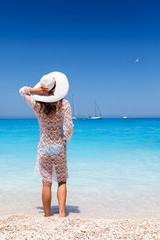 Attraktive Touristin in weißem Strandkleid genießt das türkisblaue Meer der Ionischen Inseln in...