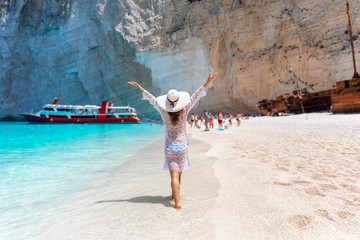 Attraktive Frau in weißem Sommerkleid genießt den Shipwreck Strand mit türkisem Meer auf...