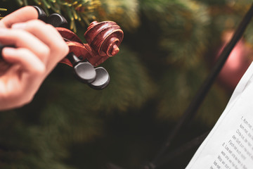 ein Mädchen spielt am Weihnachtsbaum auf einer Violine neben dem Notenständer mit Notenblatt	