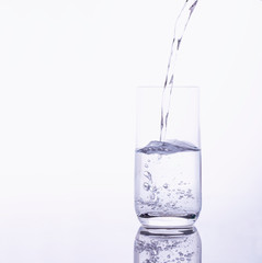 Wasser wird sprudelnd in ein Glas geschüttet