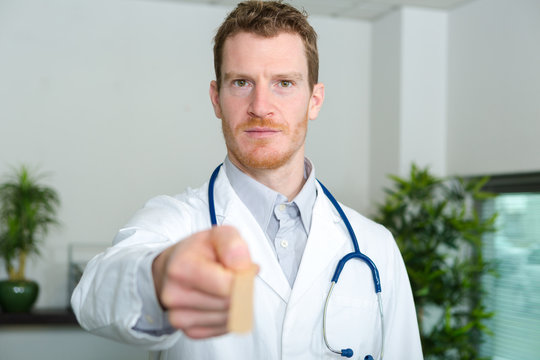 doctor holding forwards a wooden spatula for checking throat