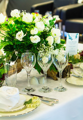 wedding party dinner table setting with tableware and silverware and glasses set and Candlestick and flower in restaurant.