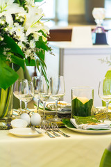 Party dinner table setting with tableware and silverware and glasses set and Candlestick and flower in restaurant.