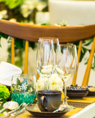 Party dinner table setting with tableware and silverware and glasses set and Candlestick and flower in restaurant.