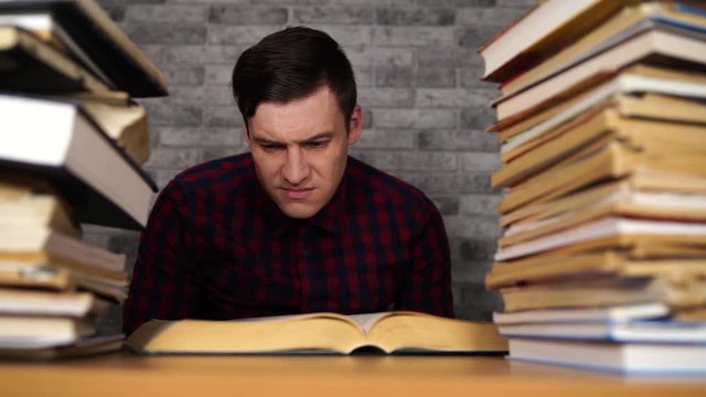 Man student boring reading book at library with a lot of books in university.