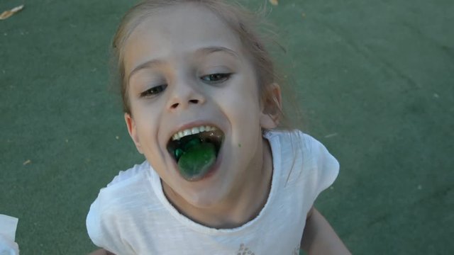 smiling little girl with green tongue from lollypop