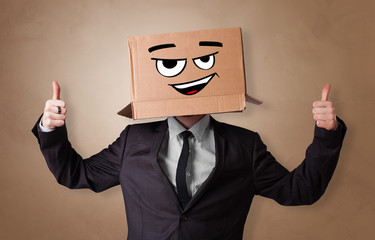 Young man with happy face illustrated cardboard box on his head
