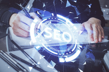 Multi exposure of woman's hands making notes with SEO icon. Concept of Search engine optimization
