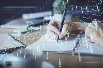 Financial forex graph drawn over hands taking notes background. Concept of research. Multi exposure