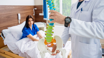 Orthopedist showing spine model to patient in hospital