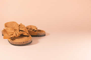 A pair of brown suede sandals are laying on a pink surface