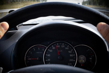 The man holds the steering wheel of the car, on the front panel are the instruments of the engine