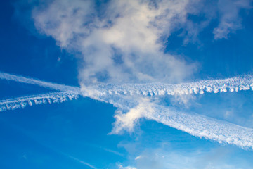 Blue sky with visible contrails of two crossing airliners.