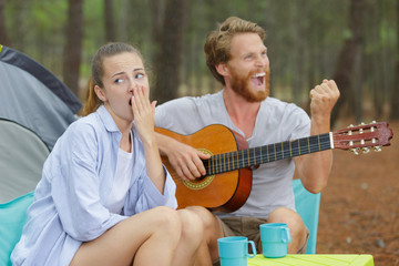 tired young woman while man playing guitar