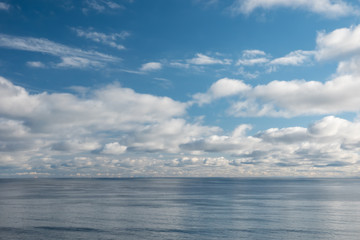 Blue sky with puffy clouds and calm sea
