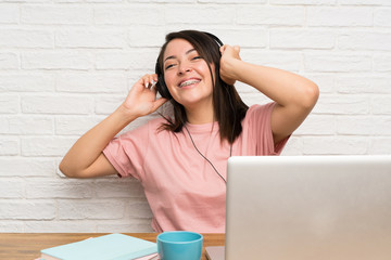 Young Mexican woman with a laptop and listening music