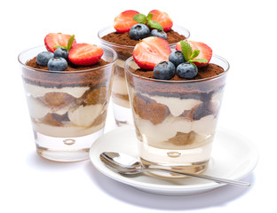 Classic tiramisu dessert with blueberries and strawberries in a glass isolated on a white background with clipping path
