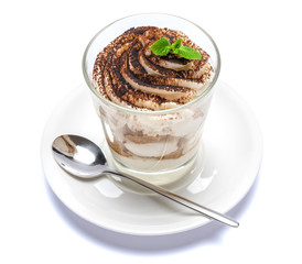Classic tiramisu dessert in a glass on plate with spoon isolated on a white with clipping path