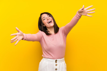 Young Mexican woman over isolated yellow background presenting and inviting to come with hand