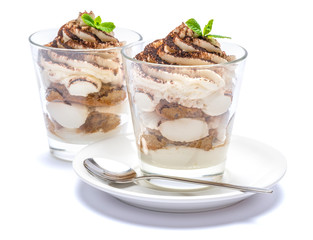 Classic tiramisu dessert in a glass on plate with spoon isolated on a white with clipping path