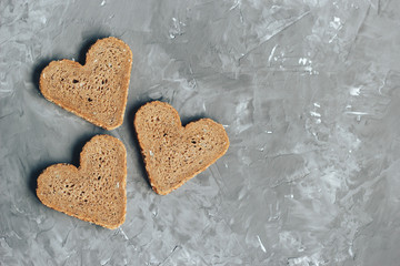 Rye bread in the shape of heart cut into slices on a gray background