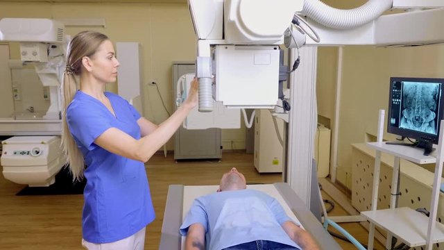 Technician ajusts X-ray Machine man lying on bed