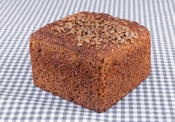 Piece of multigrain bread with sunflower seeds on top, on a blue table
