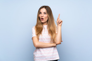 Young woman over isolated blue background thinking an idea pointing the finger up